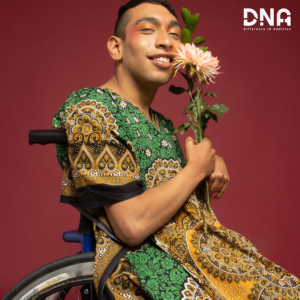 Ragazzo con disabilità con su sedia a rotelle, stringe un fiore colorato sorridendo. Vantaggi della diversità.